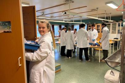 Lærer og elever i hvite lab-frakker i et klasserom.