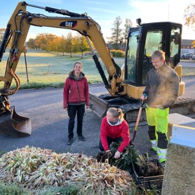 Elever i hagebrup, gravemaskin i bakgrunnen. 