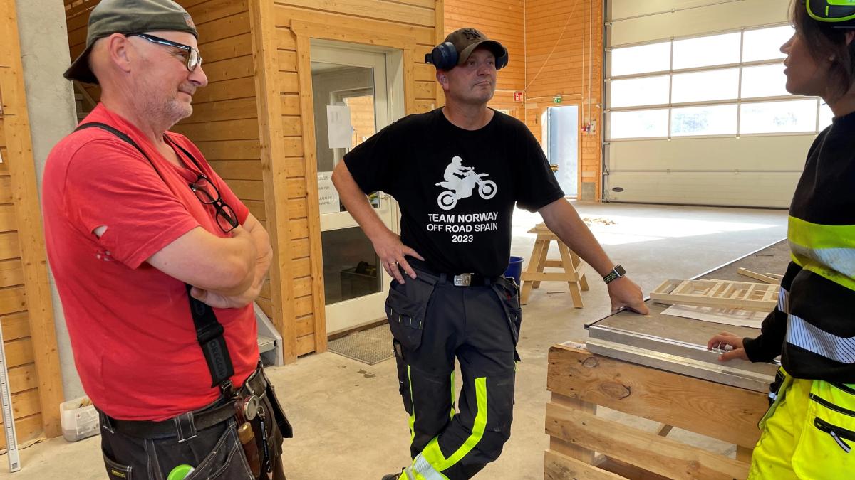 To ansatte prater med en elev i bygghallen.