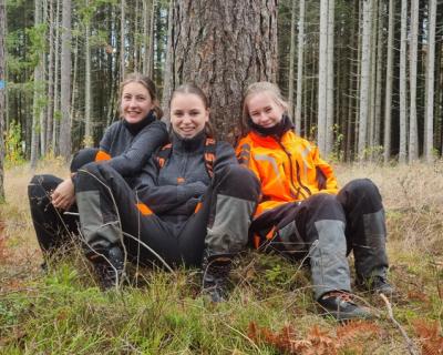 Tre jenter som sitter og lener seg inntil et tre