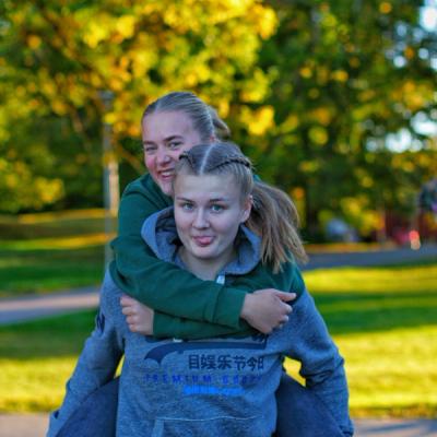 Ei jente sitter på ryggen til ei annen jente.