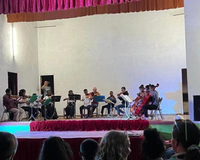 Gatebarn som spiller i orkester med instrumenter på en scene. 
