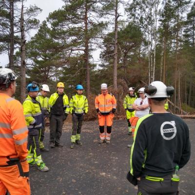 En gjeng i arbeidsklær står i ring. 
