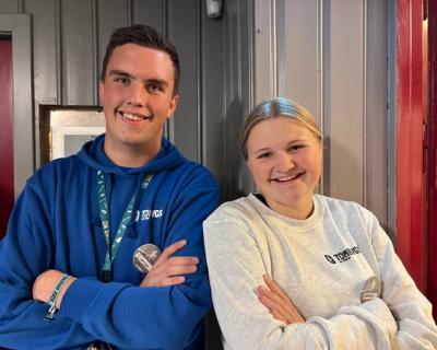 To studenter, gutt og jente smiler til kamera.