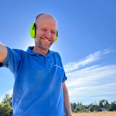 Olav Røyneberg på treskeren, stort smil. 